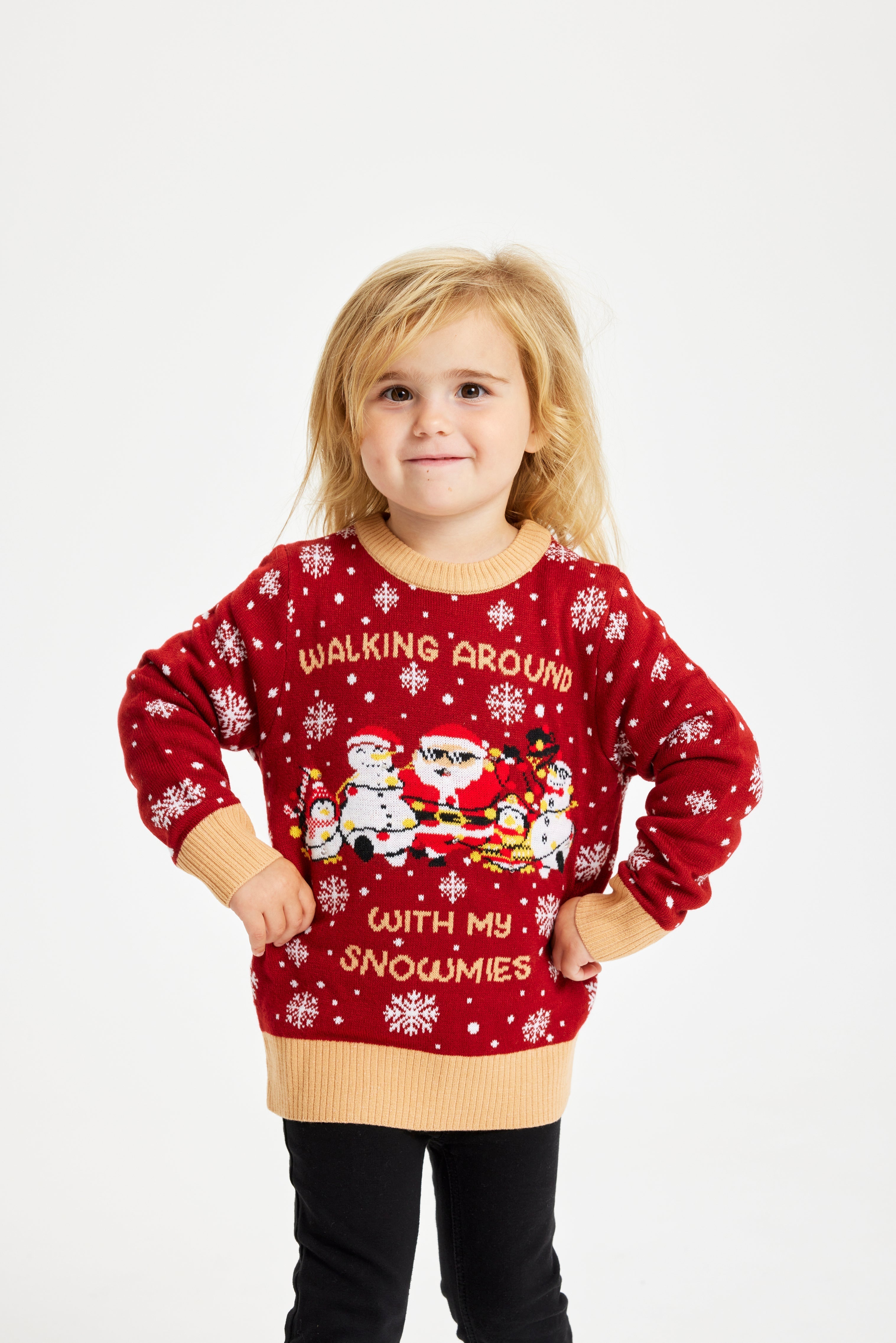 Un bambino sorridente che indossa un maglione natalizio rosso con la scritta